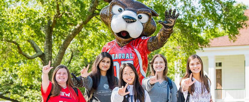 Students holding up J sign in front of Southpaw statue.