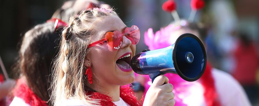 Sorority member yelling into microphone at bid day.